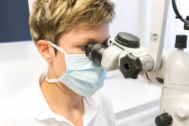 Zahnärztin bei der Wurzelbehandlung mit dem Dentalmikroskop – Zahnarztpraxis in Langfort, Langenfeld